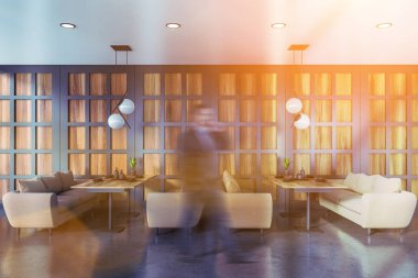 Gri lüks restoranda yürüyen bir işadamı.