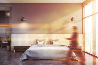 Gri yatak odasında yürüyen adam.