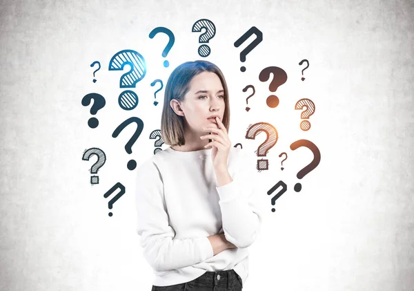 Thoughtful young casual woman, question marks — Stock Photo, Image