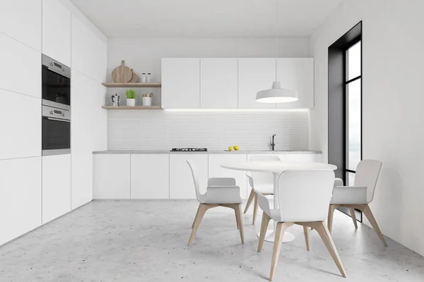 White kitchen with ovens and round table — 스톡 사진