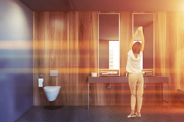 Mujer en baño de madera con lavabo e inodoro — Foto de Stock