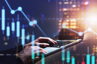 Şehirdeki dizüstü bilgisayarda yazan adam, finansal grafik