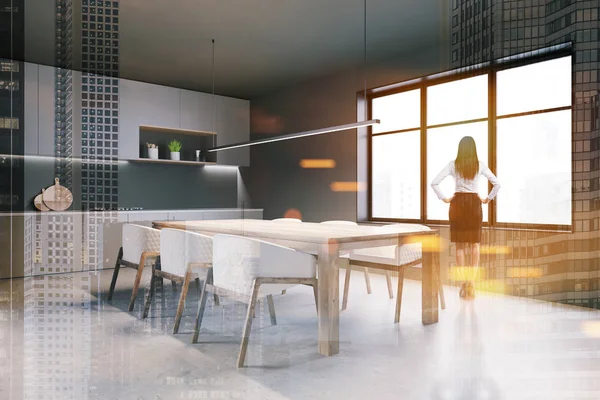 Woman in gray kitchen with table — 스톡 사진