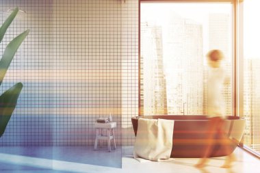 Küveti ve duşu olan beyaz fayanslı banyoda bir kız.