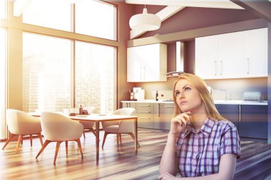 Gri mutfakta masalı düşünceli bir kadın.