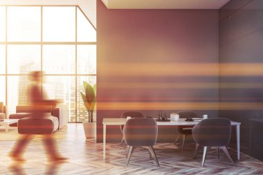 Adam gri yemek odasında ve oturma odasında yürüyor.