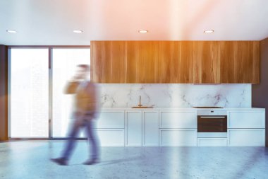Man walking in white marble and gray kitchen