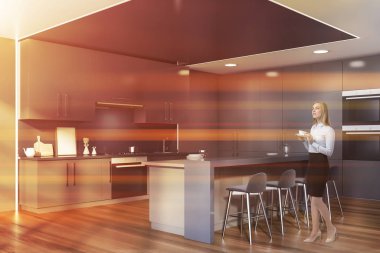 Gri mutfak köşesinde bar sahibi sarışın bir kadın.