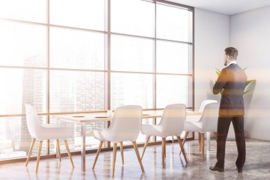 Masası olan beyaz yemek odasında bir adam.