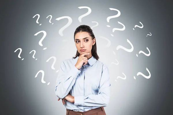 Thoughtful young woman and question marks — Stock Photo, Image