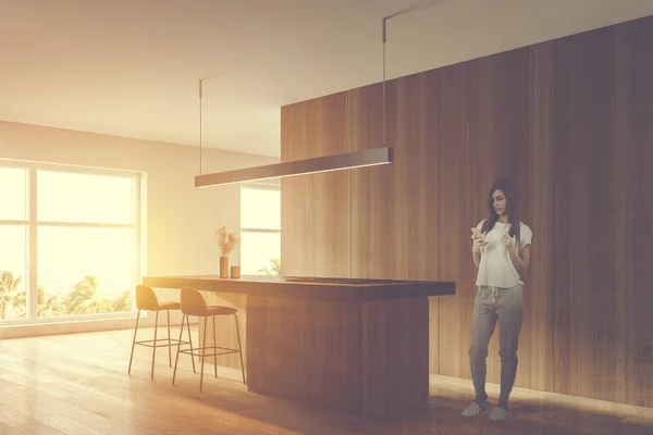 Jovem mulher na cozinha branca e de madeira com bar — Fotografia de Stock