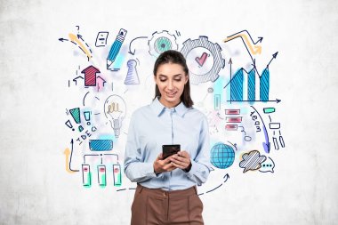Üzerinde renkli iş stratejisi çizimi olan beton duvarın yanında akıllı telefon kullanan koyu renk saçlı, gülümseyen genç bir iş kadını. İş planı kavramı. Bulanık resim