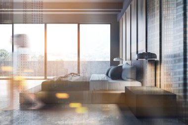 Geniş yatak odasında gri ve ahşap duvarları, taş zemini, rahat kral yatağı ve güzel manzaralı balkonu olan bulanık genç bir kadın. Renkli resim çift pozlama