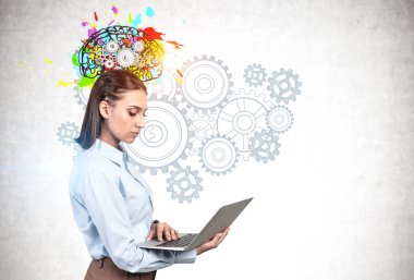 Üzerinde vites çizilmiş renkli beyin çizimi olan beton duvarın yanında duran ciddi genç kadın mühendis. Beyin fırtınası ve yaratıcılık kavramı. Model