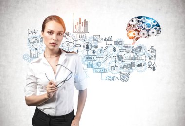 Dişli beyinli, beton duvarın yanında duran, kendine güvenen genç iş kadını. Üstüne de yaratıcı bir iş planı çizimi çizilmiş. İş stratejisi kavramı