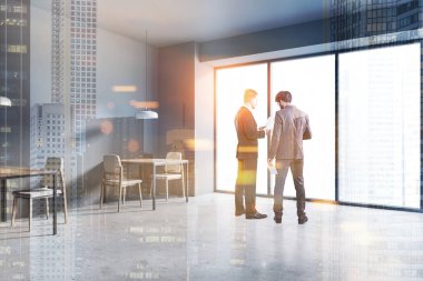 Gri duvarları, beton zemini ve kare masaları olan panoramik ofis restoranında belgeleri tartışan iki genç yönetici. Bulanık şehir manzarası. Renkli resim çift pozlama