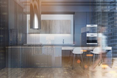 Gri ve beyaz duvarları, gri tezgahları, tabureli barları ve fırınları olan modern mutfakta yürüyen bulanık genç bir kadın. Renkli resim çift pozlama