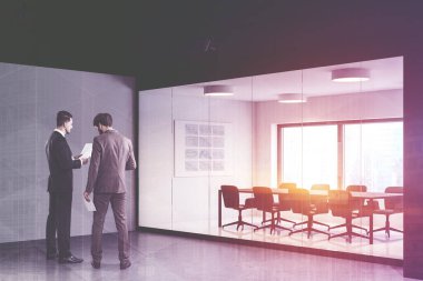İki başarılı iş adamı modern ofis toplantı odasının yakınında beyaz ve cam duvarları, uzun konferans masası ve beyaz tahtada grafikleri olan işleri tartışıyor. Renkli resim çift pozlama