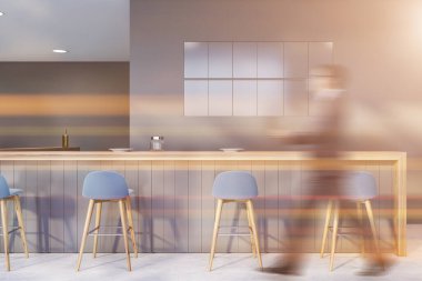 Gri duvarları, beton zemini, uzun bar tezgahı ve mavi tabureleriyle modern barda yürüyen bulanık genç adam. Tonu ayarlanmış resim