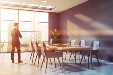 Modern panoramik kafenin içinde gri duvarları, beton zemini ve mavi sandalyeli uzun yemek masası olan genç iş adamının arka görünüşü. Tonu ayarlanmış resim