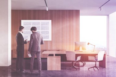 İki genç yönetici panoramik CEO ofisinde, beyaz ve ahşap duvarları, devasa bilgisayar masası ve ziyaretçiler için sandalyeleri olan belgeleri tartışıyor. Liderlik kavramı. Renkli resim çift pozlama