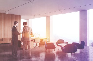 İki genç iş adamı, beyaz ve ahşap duvarları olan güneş ışığında CEO ofisinde konuşuyor. Devasa bilgisayar masası ve mavi koltuklu dinlenme odası. Yönetim kavramı. Renkli resim çift pozlama