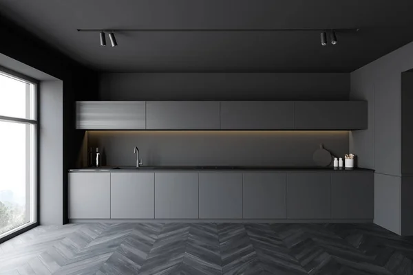 Interior of minimalistic kitchen with grey walls, dark wooden floor, gray countertops with built in sink and cooker, dark wooden cupboards and window with mountain view. 3d rendering