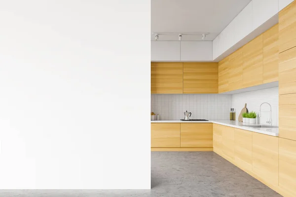 Interior of minimalistic spacious kitchen with white tile walls, concrete floor, wooden cupboards and countertops with built in appliances. Mock up wall to the left. 3d rendering
