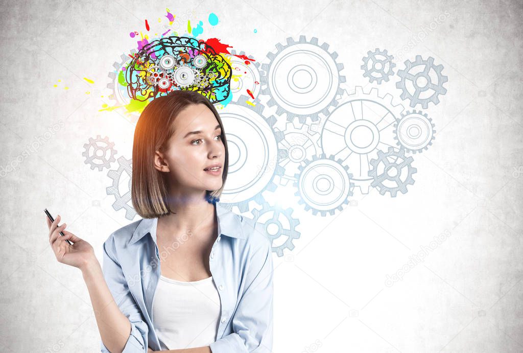 Thoughtful young woman in smart casual clothes standing near concrete wall with colorful brain with gears drawn on it. Concept of brainstorming and creativity.