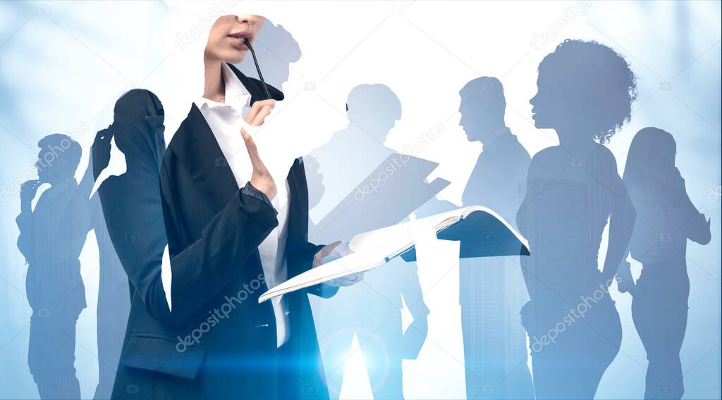 Unrecognizable young businesswoman with notebook and glasses standing over blurry background with double exposure of her diverse business team. Concept of leadership. Toned image