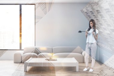 Minimalist oturma odasında beyaz duvarları, rahat kanepesi ve Japon tarzı masası olan genç bir kadın. Bulanık şehir manzaralı bir pencere. Renkli resim çift pozlama