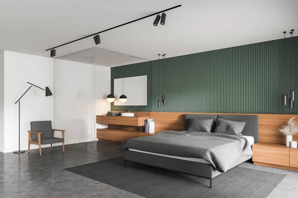Corner of stylish master bedroom with green and white walls, concrete floor, comfortable king size bed and glass wall bathroom with sink. Cozy armchair with floor lamp. 3d rendering