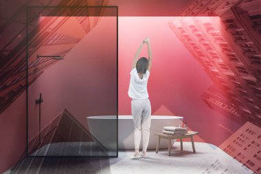 Parlak banyoda kırmızı duvarları, beton zemini, rahat küveti ve duş kabini olan pijamalı genç bir kadın. Spa konsepti. Renkli resim çift pozlama