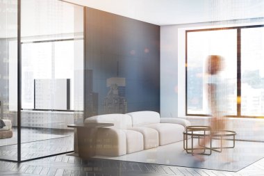 Geniş oturma odasında siyah beyaz duvarları olan, yuvarlak kahve masaları olan rahat bir kanepe ve yanında televizyon olan yatak odası olan bulanık genç bir kadın. Renkli resim çift pozlama