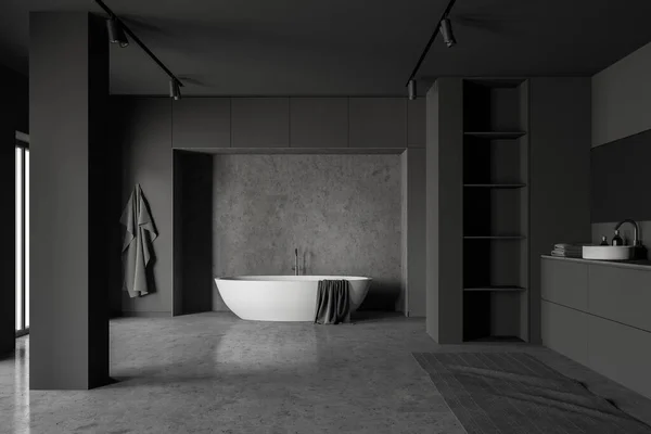 Interior of spacious loft bathroom with grey and concrete walls, concrete floor, comfortable bathtub and round sink with shelves next to it. 3d rendering
