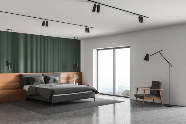 Corner of spacious master bedroom with green and white walls, concrete floor, comfortable king size bed with wooden bedside tables and gray armchair with floor lamp. 3d rendering