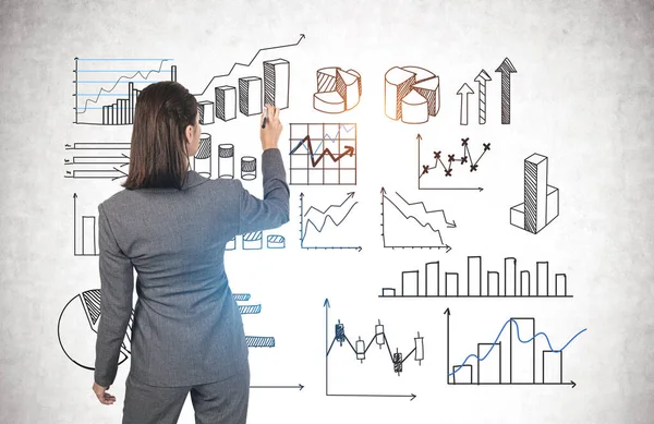 コンクリート壁にグラフの暗い髪の描画タイプのビジネス女性の教師の背面図 統計及び事業報告の概念 — ストック写真
