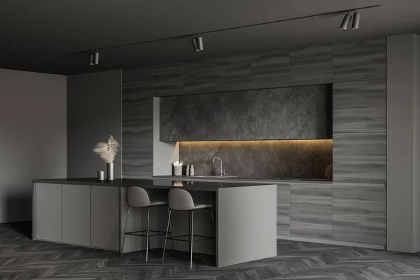 Corner of minimalistic kitchen with grey walls, dark wooden floor, comfortable bar with stools, wooden countertops and grey cupboards above them. 3d rendering