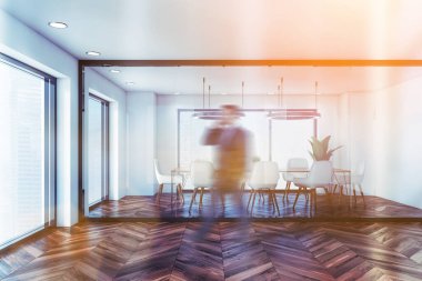 Bulanık genç işadamı, beyaz ve cam duvarlı modern konferans odasının önünden geçiyor. Koyu ahşap zemin ve fütürist tavan lambaları. Yönetim kavramı. Simgeli resim