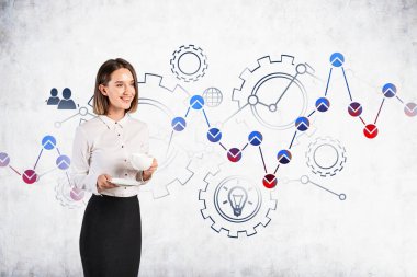 Kahvesi beton duvarın yanında duran neşeli, genç bir iş kadını. Üzerinde finansal çizim ve iş çizimi var. İş stratejisi kavramı