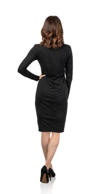 Siyah elbiseli, kahverengi dalgalı saçlı, ileri doğru yürüyen Avrupalı genç iş kadınının tam boy portresi. Arka görünüm