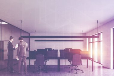 Beyaz ve cam duvarları, beton zemini ve sıra sıra siyah bilgisayar masaları ve dosya dolaplarıyla modern açık uzay ofisinde konuşan iki işadamı. Renkli resim çift pozlama