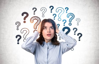 Üzerinde soru işaretleri olan beton duvarın yanında duran koyu renk dalgalı saçlı genç iş kadını ya da öğrenci portresi. Sorun çözme ve seçim kavramı.