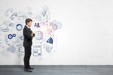 Üzerinde yaratıcı bulanık sosyal medya ve iş planı çizimi olan beton duvarın yanında duran kendine güvenen genç Avrupalı işadamının yan görünüşü. Model