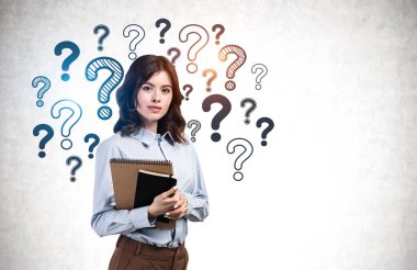 Üzerinde soru işaretleri olan beton duvarın yanında duran ciddi bir Avrupalı genç iş kadını ya da öğrenci. Eğitim ve seçim kavramı. Model