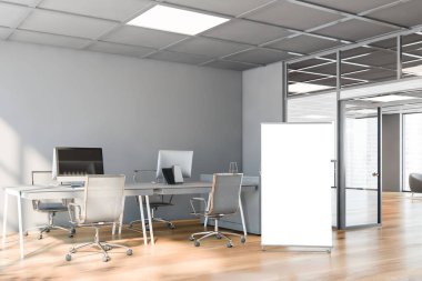 Gri duvarları, ahşap zemini, beyaz bilgisayar tabloları ve dikey poster çerçevesi olan şık bir açık uzay ofisi. Reklam kavramı. 3d oluşturma