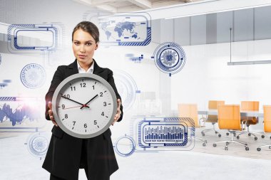 Beautiful young businesswoman showing big clock in blurry office with double exposure of futuristic immersive graphical user interface. Concept of hi tech. Toned image clipart