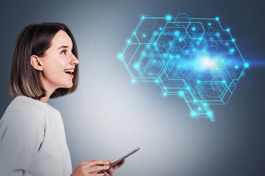 Akıllı telefonlu mutlu genç bir kadının portresi gri arka planda bulanık yapay zeka beyin hologramına bakıyor. Makine öğrenme kavramı. Tonu ayarlanmış resim