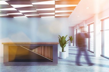 Bulanık, genç bir işadamı beyaz duvarlar, fayanslı döşemeler ve gri resepsiyon masasıyla ofis salonunda yürüyor. Şirket hayatı kavramı. Tonu ayarlanmış resim