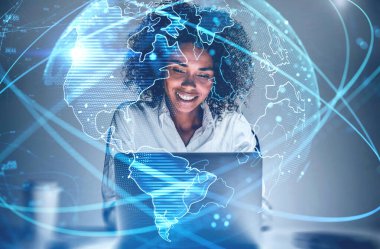 Bulanık ofiste dizüstü bilgisayar kullanan neşeli, genç Afrikalı Amerikalı bir kadın. Fütürist ağ arayüzü ve gezegen hologramına iki kez maruz kalmış. İnternet ve iletişim kavramı. Tonu ayarlanmış resim